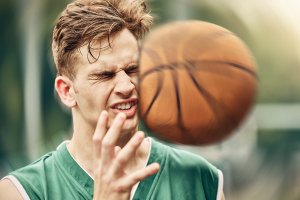 Young man playing basketball, illustrating sudden injuries accident insurance for employees in California helps cover.