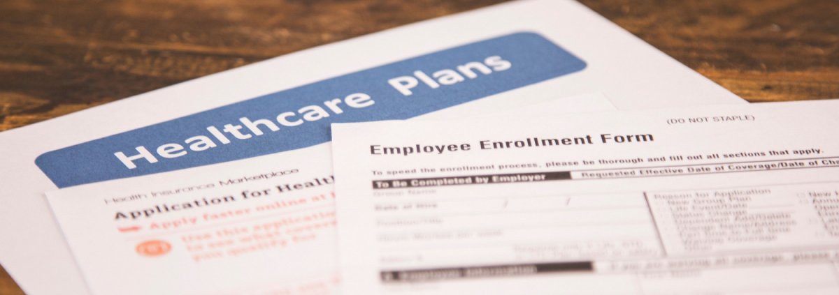 A desk with papers related to healthcare plans and employee enrollment forms.